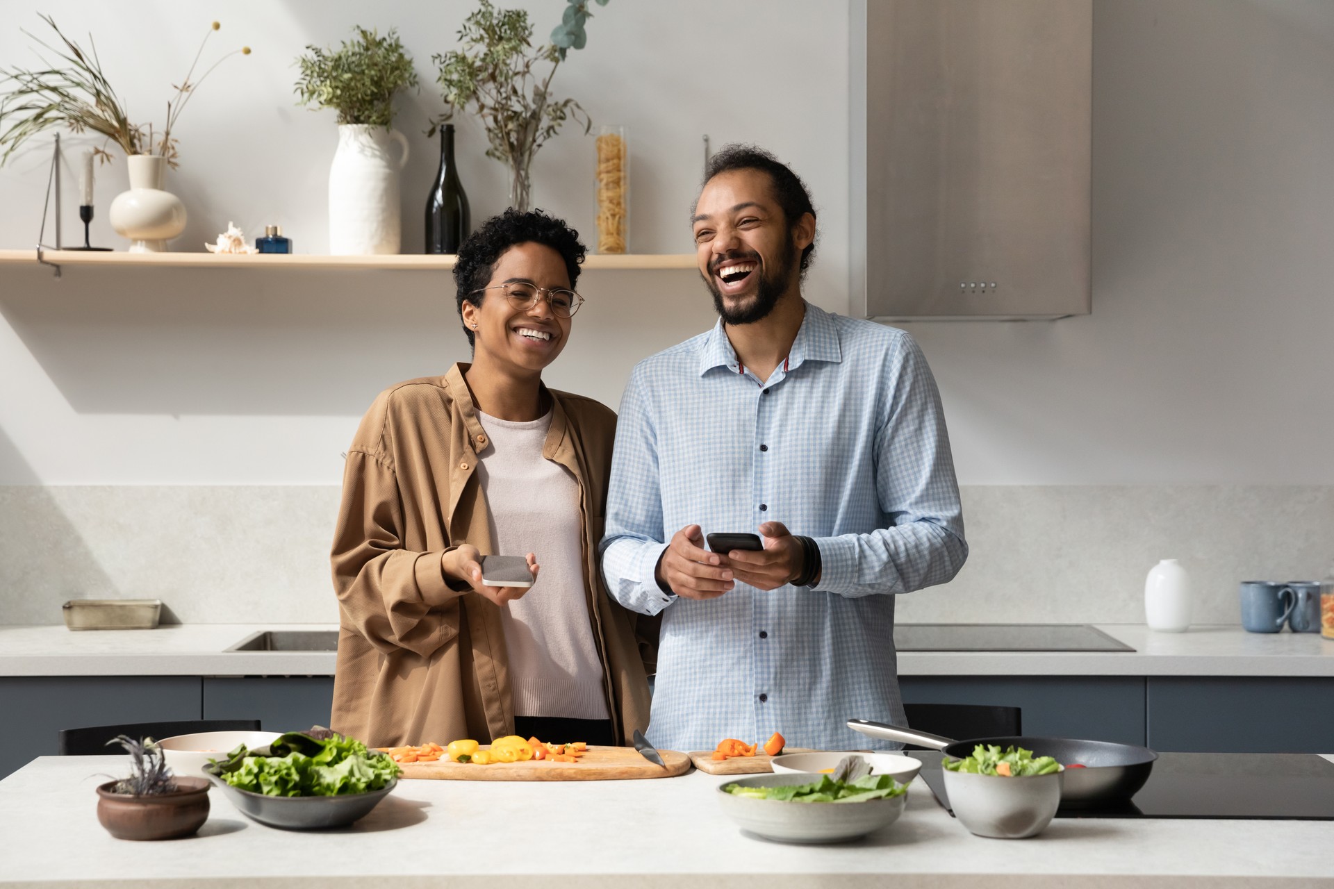 Happy cheerful young dating African couple cooking dinner together