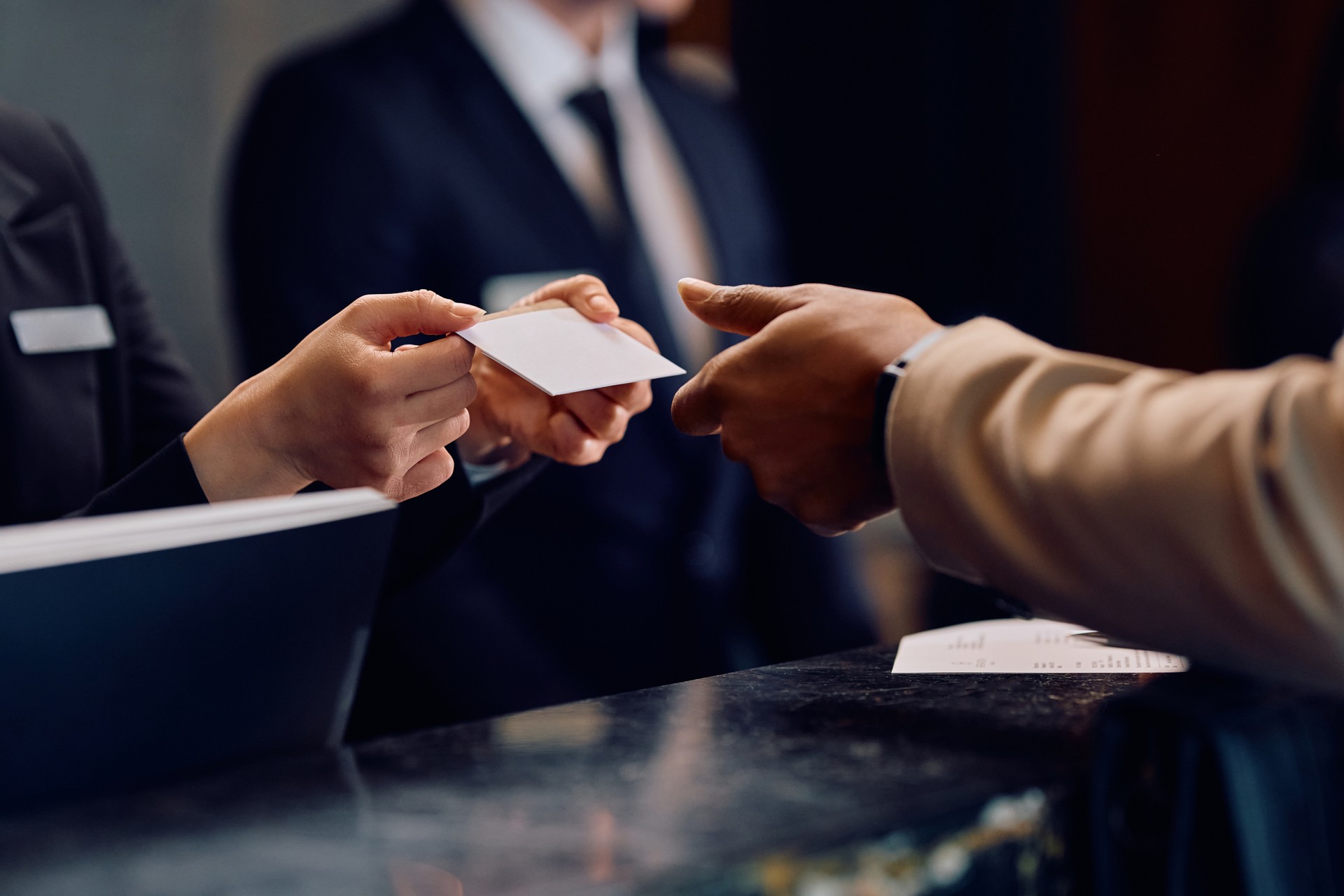 Close up of black man receiving room cardkey while checking in at the hotel.