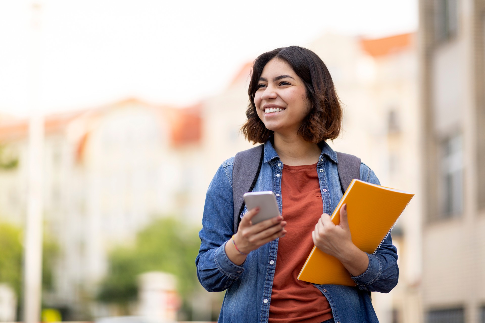 Cheerful Arab Female Student With Smartphone And Workbooks Standing Outdoors